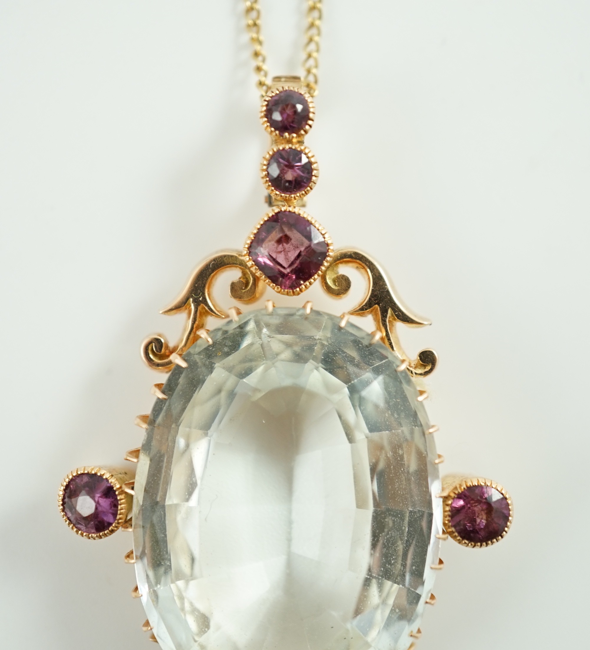 An early 20th century gold, aquamarine and garnet cluster set drop pendant, on a gold fine link chain